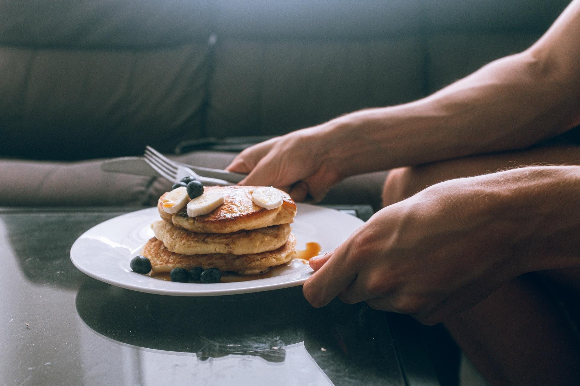 Un uomo con in mano un pancake di farina d'avena alla banana